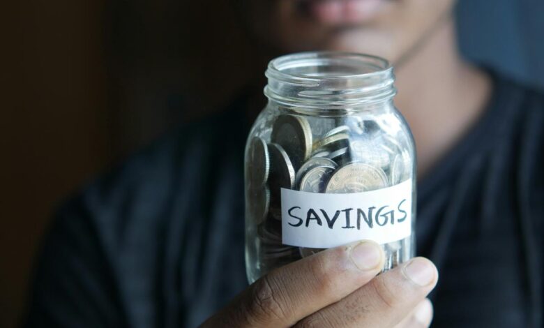 a man holding a jar with a savings label on it
